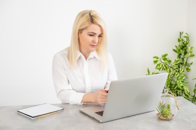 Frauenlaptop online gegen weißen Wandhintergrund