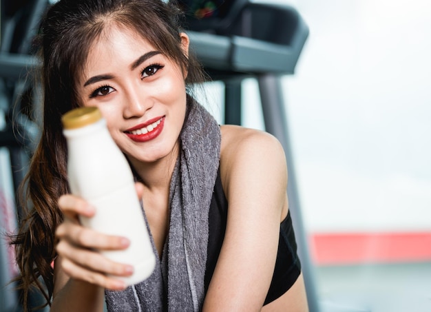 Frauenlebensstil, der nach dem Training im Fitness-Studio Milch schüttelt