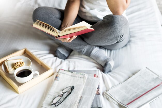 Foto frauenlesebuch oder -zeitung und trinkendes kaffeefrühstück