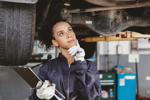 Frauenmechaniker-Arbeiterdenken. Garagenpersonal weiblich denken Tagtraum oder vergessen Checkliste Autoservice.