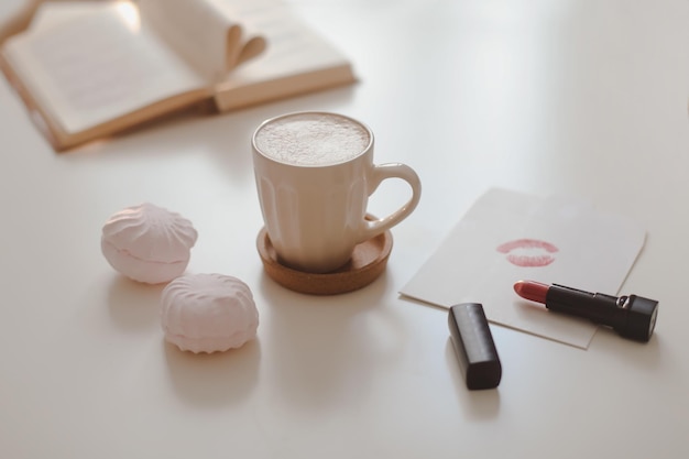 Frauenmode flach lag mit Kaffeetassenbuch und roten Lippenstiftaccessoires und Kosmetika auf weißem Rücken...