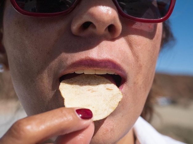 Frauenmund, der Kartoffelchips hautnah isst