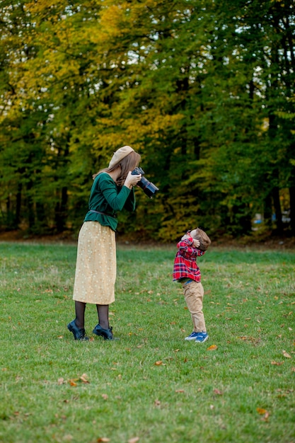 Frauenphotograph, der das Kind fotografiert, um draußen im Park zu verbringen