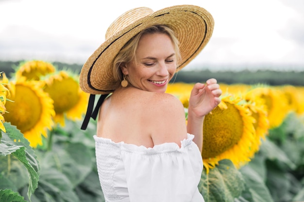 Frauenporträt in einem Strohhut in einem weißen Kleid ein Feld der Sonnenblumen-Landwirtschaft unverändert