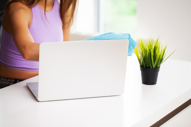 Frauenreiniger räumt den Computertisch im Büro auf