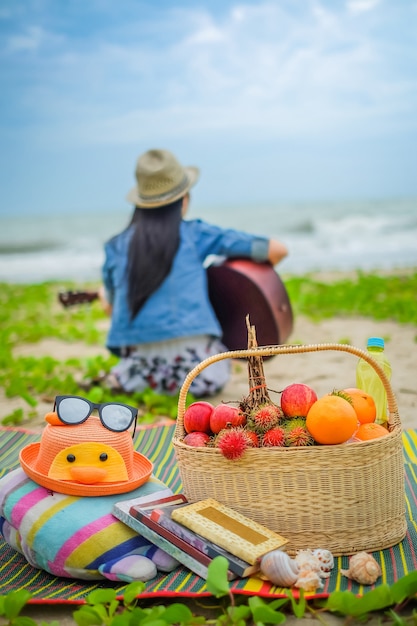 Frauenreisender, der eine Gitarre und ein Picknick auf dem Strand spielt.