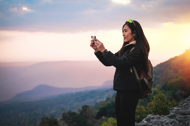 Foto frauenreisender, der oben auf dem berg steht und fotoansicht der natur im urlaub nimmt.