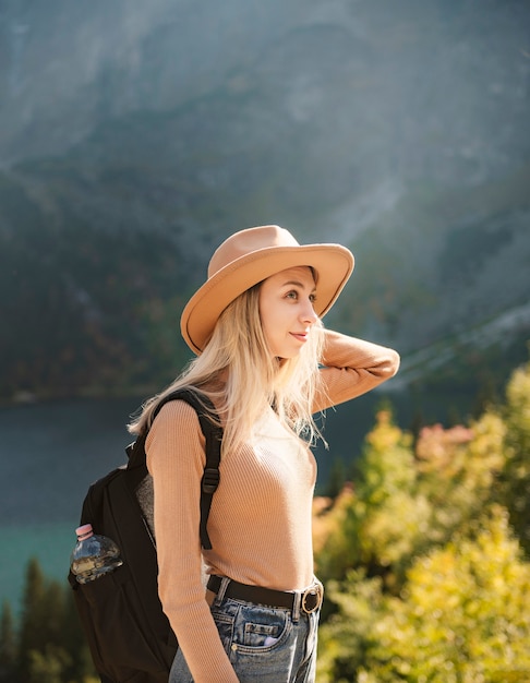 Frauenreisender mit Hut und Blick auf erstaunliche Berge und See, Fernweh-Reisekonzept. See Morskoy Eye in der polnischen Tatra.