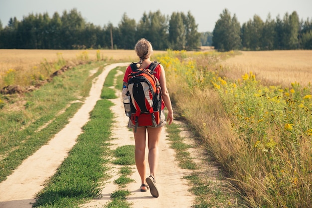 Frauenreisender mit Rucksack, der in Bergen mit schöner Sommerlandschaft wandert