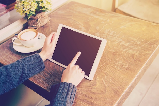 Frauenspiel-Tablet-Computer in der Kaffeestube mit Weinleseton.