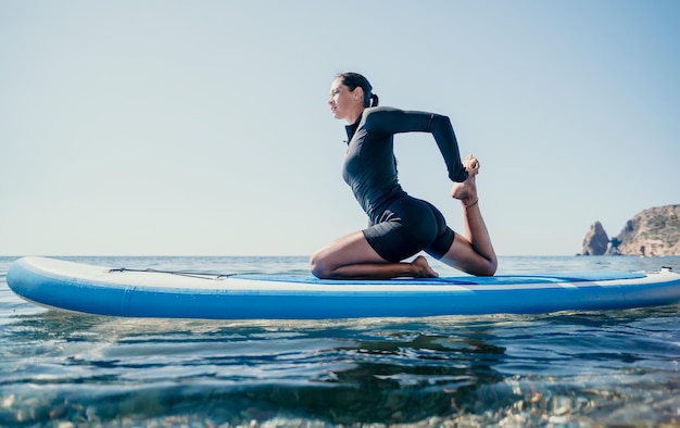 Frauensup-Yoga glückliche sportliche Frau übt Yoga-Pilates auf Paddle-Sup-Surfbrett Weibliche Dehnung