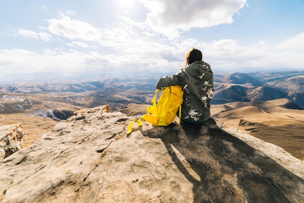 Frauentourist sitzt auf einem Hintergrund von hohen Bergen