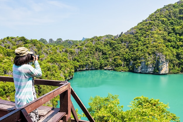 Foto frauentouristen auf dem aussichtspunkt der insel koh mae ko verwenden eine kamera, die fotos in der wunderschönen naturlandschaft von thale nai oder der blauen lagune (smaragdsee) im mu ko ang thong nationalpark, surat thani, thailand macht