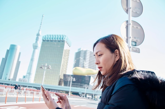 Frauentouristin mit Smartphone in Tokio Japan