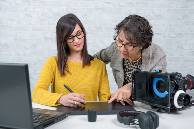 Frauenvideoeditor und junger Assistent, der grafische Tablette verwendet