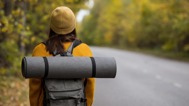 Frauenwanderer geht auf leerer Straße und erkundet Herbstwald