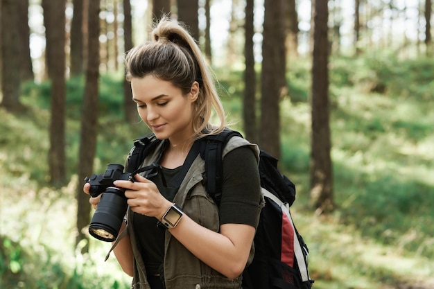 Frauenwanderer mit moderner spiegelloser Kamera im grünen Wald