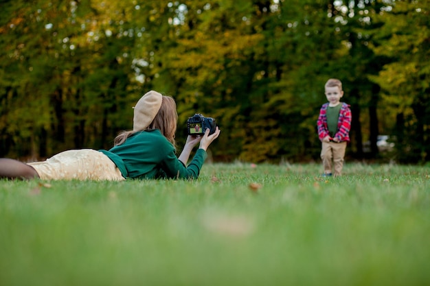 Frauliche Fotografin fotografiert das Kind, um es im Park zu verbringen