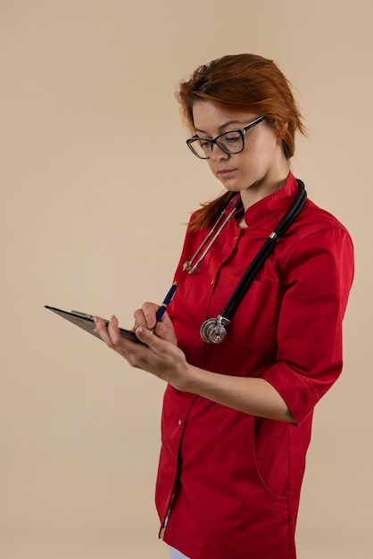 Frauliche Ärztin in roter Uniform oder medizinische Assistentin hält die Schreibtafel isoliert