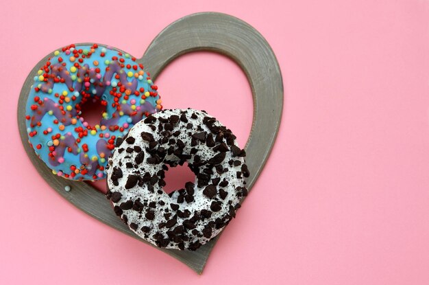 Freah zwei Donuts in einem herzförmigen Rahmen auf einem rosa Hintergrund