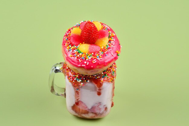 Freakshake Extreme milk-shake com rosquinha de doces de geléia de morango em fundo verde