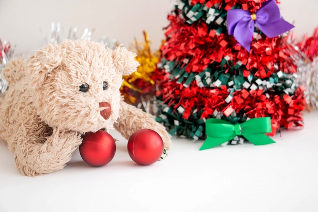 Freche Teddybär spielt eine rote Kugel schmücken Weihnachtsbaum