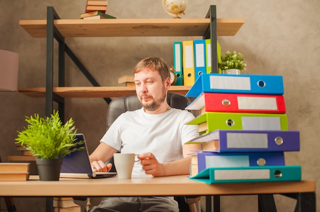 Freelance masculino en casa trabajando en una computadora portátil.