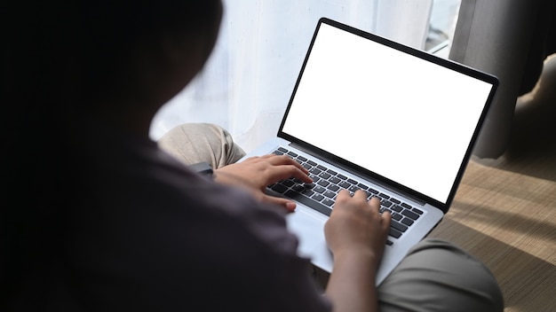 Freelance de mujer joven sentada en el suelo y trabajando en la computadora portátil.