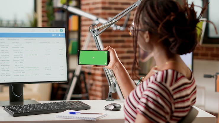 Foto freelancer afroamericano usando pantalla verde horizontal en el teléfono móvil, mirando una plantilla de maqueta aislada con fondo de clave de croma y espacio de copia en blanco. sosteniendo teléfono inteligente.