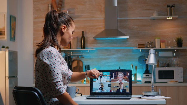 Freelancer apagando la computadora portátil durante el seminario web en medio de una videoconferencia sentado en la cocina trabajando hasta altas horas de la noche de forma remota. Uso de la red inalámbrica de tecnología moderna