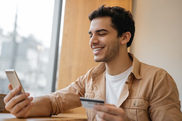 Freelancer asiático com cartão de crédito usando telefone celular recebe pagamento