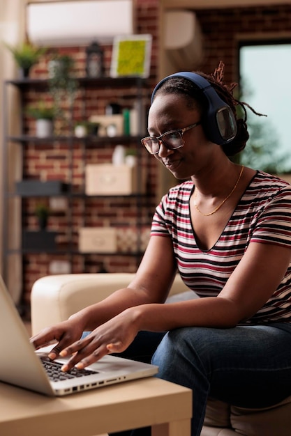 Freelancer en auriculares trabajando en una computadora portátil, escuchando música en la oficina en casa. trabajador remoto en auriculares, estudiante viendo tutoriales educativos de cursos en línea, videos entretenidos