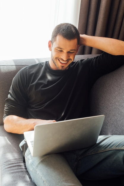 Freelancer barbudo y feliz usando laptop en casa