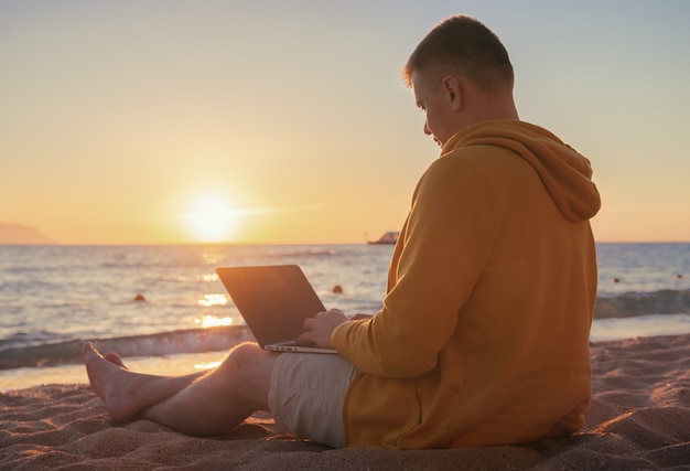 Freelancer by the sea trabajando con una computadora portátil al amanecer
