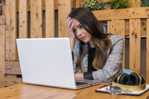 Freelancer cansado leyendo mal informe en la computadora portátil durante el trabajo en línea