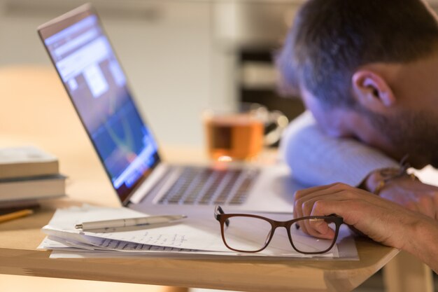 Freelancer cansado turva dormindo depois do trabalho no laptop