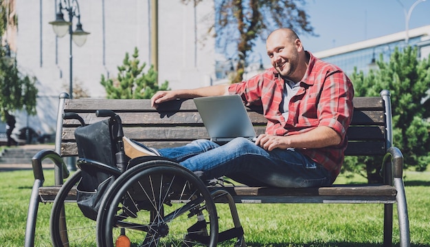 Freelancer com deficiência física que usa cadeira de rodas trabalhando no parque
