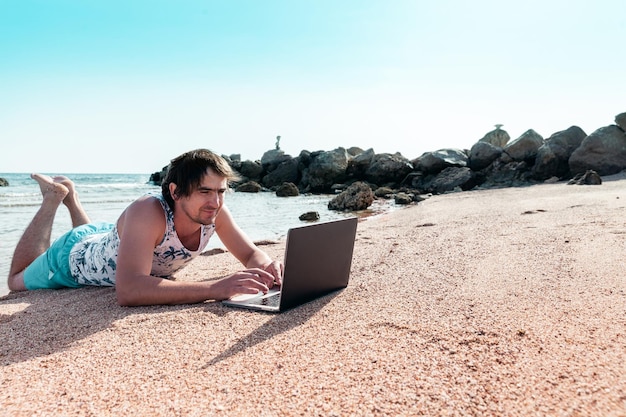 Foto freelancer con una computadora portátil trabaja en una playa