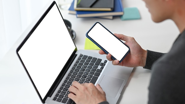 Foto freelancer de homem trabalhando com computador portátil e usando o smartphone.