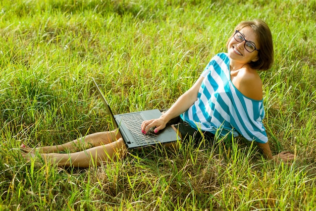 Freelancer de mulher bonita trabalhando com laptop ao ar livre