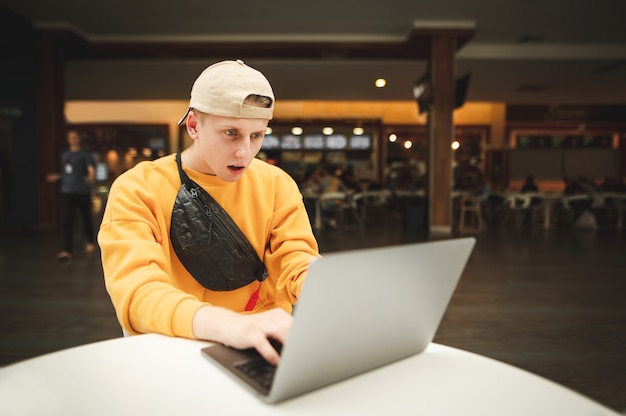 Freelancer de emoción joven en ropa casual trabaja en un centro comercial