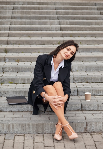 La freelancer es una emprendedora con una laptop en las escaleras, tiene un descanso