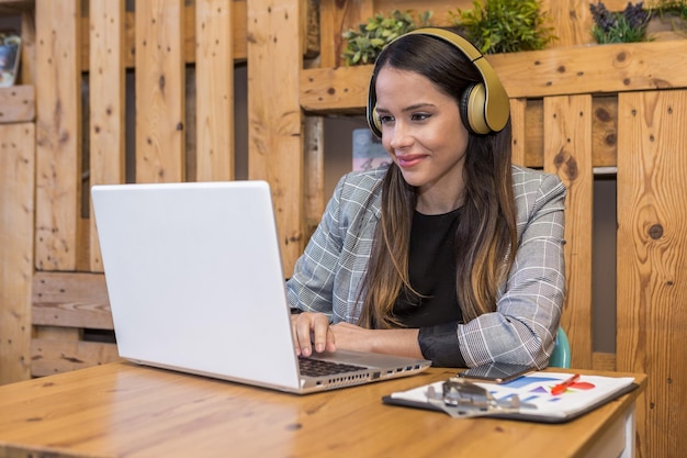 Foto freelancer femenino en auriculares usando laptop en cafe