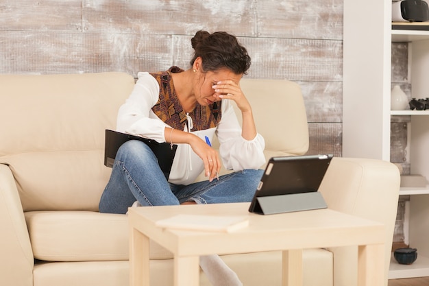 Freelancer feminina cansada enquanto trabalhava em casa durante uma videoconferência.