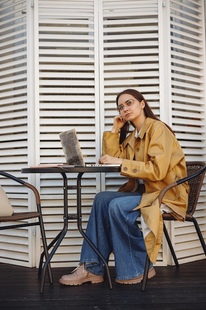 Freelancer feminina pensativa trabalhando em laptop no café da cidade e pensando em projeto de negócios