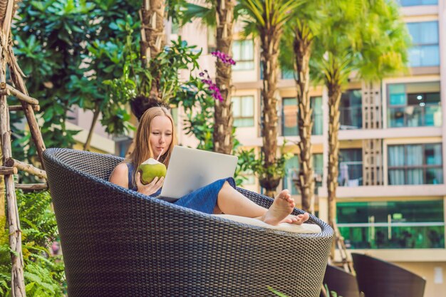 Freelancer feminino jovem sentado perto da piscina com seu laptop. ocupado nos feriados. conceito de trabalho distante. copie o espaço para o seu texto