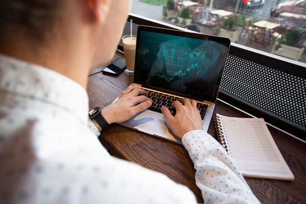 Foto freelancer hombre trabajando en un portátil en la cafetería.