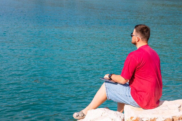 Freelancer hombre trabajando en un portátil en el verano del banco del puerto de la ciudad