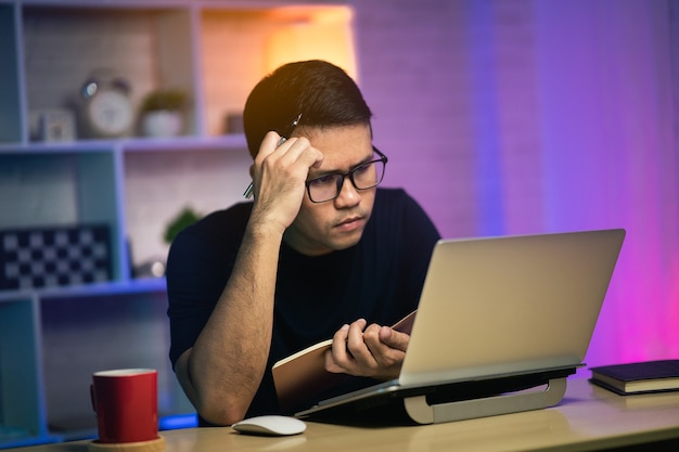 Freelancer homem sério e ocupado trabalhando com o laptop em cima da mesa, conceito de trabalho em casa