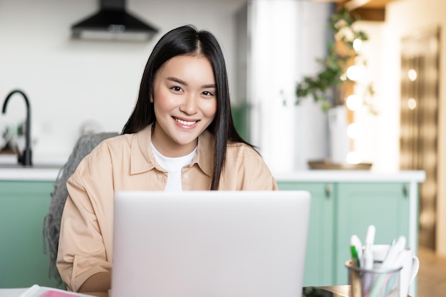 Freelancer jovem asiática trabalhando remotamente de casa, mulher com laptop, estudando dentro de casa de seu k.